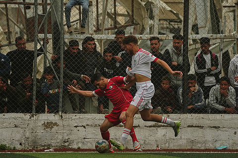 Palestinian players of Gaza Sports Club, top center, and Al-Ahly Club, left, vie for the ball during a soccer match at a newly constructed field surrounded by buildings destroyed in Israeli ground and air operations, in Gaza City.5