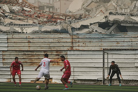 A Palestinian player of Gaza Sports Club, center left, kicks the ball during a soccer match with Al-Ahly Club at a newly constructed field surrounded by buildings destroyed in Israeli ground and air operations, in Gaza City.