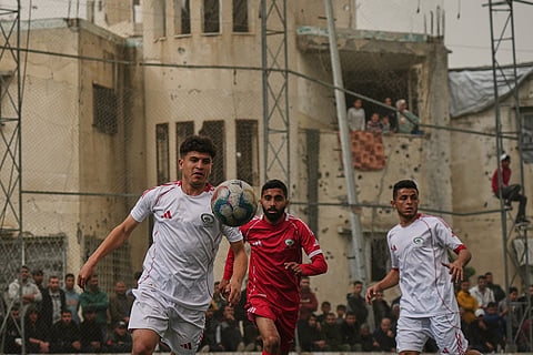 A Palestinian player of Gaza Sports Club, left, controls the ball during a soccer match with Al-Ahly Club at a newly constructed field surrounded by buildings destroyed in Israeli ground and air operations, in Gaza City.