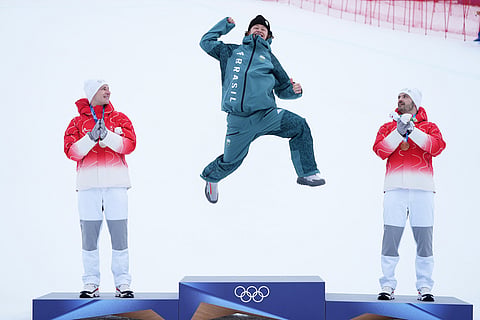 Brazil's Lucas Pinheiro Braathen, center, celebrates winning a gold medal for an alpine ski, men's giant slalom race, as silver medalist Switzerland's Marco Odermatt, right, and bronze medalist Switzerland's Loic Meillard applaud, at the 2026 Winter Olympics, in Bormio, Italy.