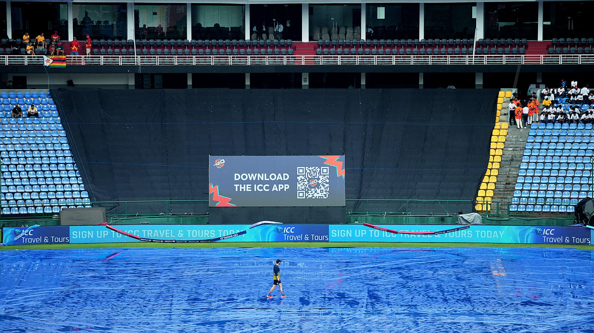 (AP Photo/Eranga Jayawardena) : A support staff member of Ireland team walks on the covered ground as rain delayed the start of play during the T20 World Cup cricket match between Ireland and Zimbabwe in Pallekele, Sri Lanka, Tuesday, Feb. 17, 202