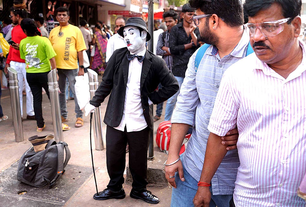 Dressed as Charlie Chaplin, Afsar Khan greets a passerby with a warm handshake on the busy streets of Dadar, sharing a moment of joy. - | Photo: Dinesh Parab/Outlook