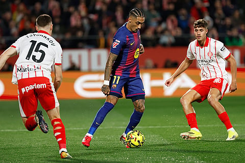 Barcelona's Raphinha fights for the ball against Girona's Viktor Tsyhankov during a Spanish La Liga soccer match between Girona and Barcelona in Girona, Spain.