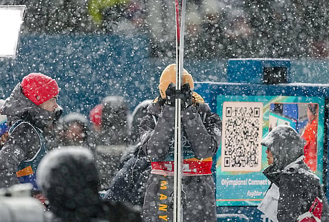 Andreas Wellinger, center, and Philipp Raimund, of Germany, left, react as a snowfall interrupts the final round jump of the ski jumping men's super team competition at the 2026 Winter Olympics, in Predazzo, Italy.