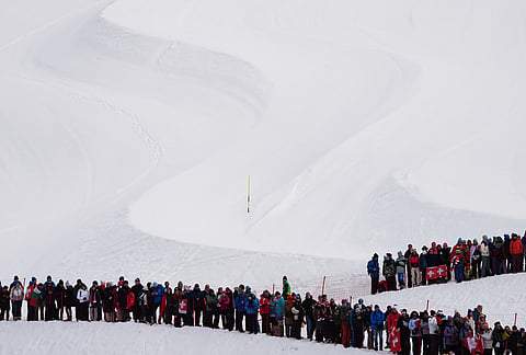 Spectators watch an alpine ski, men's slalom race, at the 2026 Winter Olympics, in Bormio, Italy.