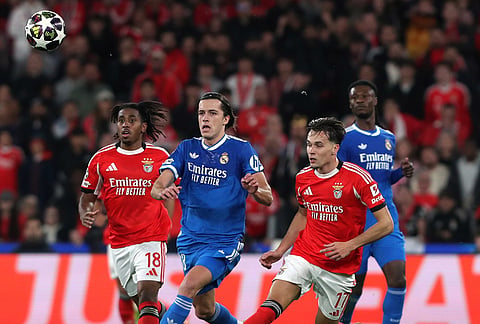 Real Madrid's Alvaro Carreras fights for the ball against Benfica's Amar Dedic and Leandro Barreiro during a Champions League playoff soccer match between SL Benfica and Real Madrid in Lisbon, Portugal.