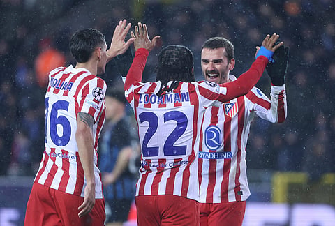 Atletico Madrid's Ademola Lookman, centre back to the camera, celebrates with Antoine Griezmann, right, and Nahuel Molina after scoring his side's second goal during the Champions League play-off first leg soccer match between Club Brugge and Atletico Madrid, in Bruges, Belgium.
