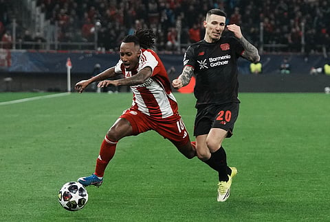 Olympiacos' Gelson Martins, left, and Leverkusen's Alex Grimaldo fight for the ball during a Champions League playoff soccer match between Olympiacos and Bayer 04 Leverkusen in Piraeus port, near Athens.