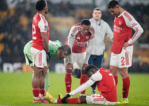 Teammates check on Arsenal's Bukayo Saka after an injury during the Premier League soccer match between Wolverhampton Wanderers and Arsenal in Wolverhampton, England.