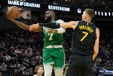 Boston Celtics guard Jaylen Brown, left, shoots against Golden State Warriors center Kristaps Porziņģis during the second half of an NBA basketball game in San Francisco.