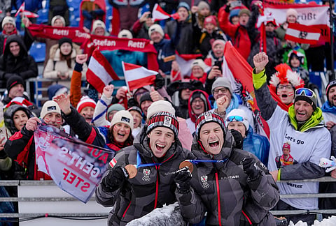 Stefan Rettenegger, left, and Johannes Lamparter, of Austria, pose with supporters after winning the bronze medal in the nordic combined team sprint at the 2026 Winter Olympics, in Tesero, Italy.