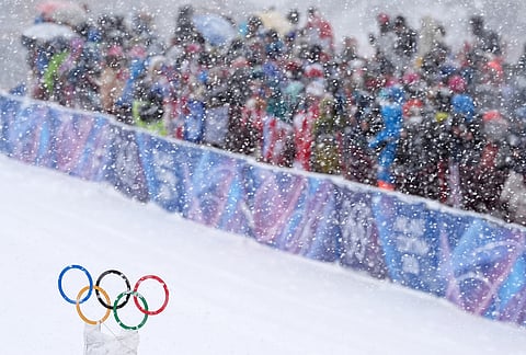 Spectators watch a ski mountaineering men's sprint heat under a snowfall at the 2026 Winter Olympics in Bormio, Italy.