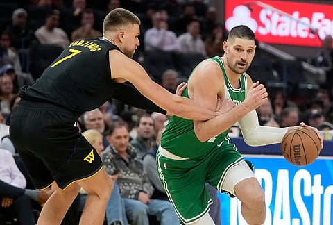 Boston Celtics center Nikola Vučević, right, drives to the basket against Golden State Warriors center Kristaps Porziņģis during the second half of an NBA basketball game in San Francisco.