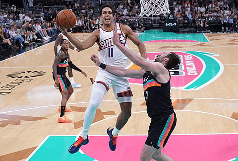Phoenix Suns forward Oso Ighodaro (11) drives to the basket past San Antonio Spurs center Luke Kornet (7) during the first half of an NBA basketball game in Austin, Texas.