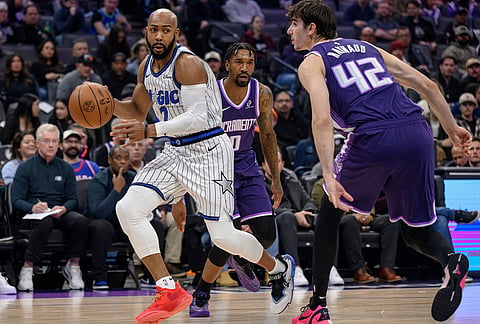Orlando Magic guard Jevon Carter, left, dribbles past Sacramento Kings guard Malik Monk (0) and center Maxime Raynaud (42) during the first half of an NBA basketball game in Sacramento, California.