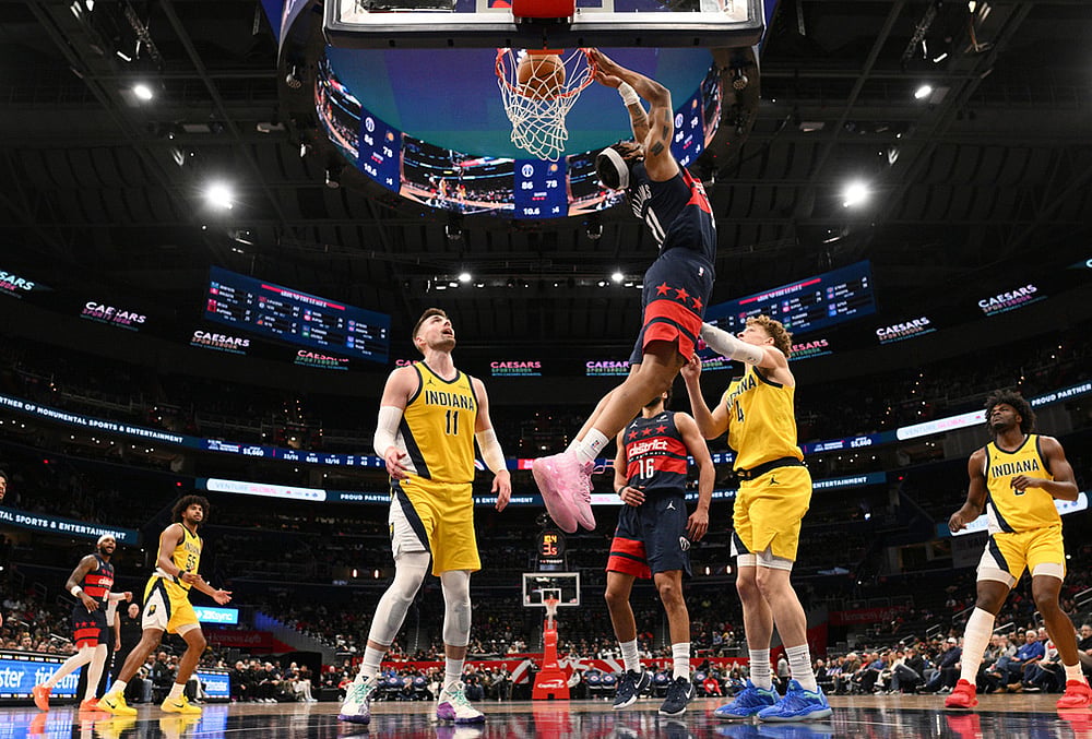 | Photo: AP/Nick Wass : Washington Wizards guard Alondes Williams (31) reverse dunks over Indiana Pacers center Micah Potter (11) and guard Taelon Peter (4) during the second half of an NBA basketball game in Washington. 