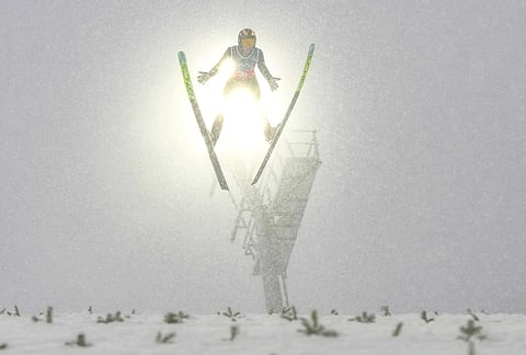 Zhao Zihe, of China, soars through the air during his competition round jump of the nordic combined team sprint at the 2026 Winter Olympics, in Predazzo, Italy.