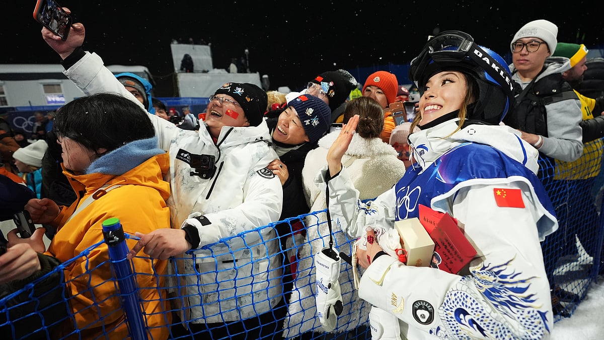 (AP Photo/Lindsey Wasson) : China's Eileen Gu takes photos with attendees after the women's freestyle skiing halfpipe qualifications at the 2026 Winter Olympics, in Livigno, Italy, Thursday, Feb. 19, 2026.