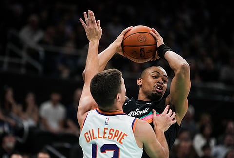 San Antonio Spurs guard Keldon Johnson (3) keeps the ball away from defense by Phoenix Suns guard Collin Gillespie (12) in the first quarter of an NBA basketball game in Austin, Texas.
