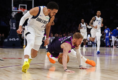 Minnesota Timberwolves' Donte DiVincenzo (0) dives for the ball against Dallas Mavericks' Tyus Jones, left, during the second half of an NBA basketball game in Minneapolis.