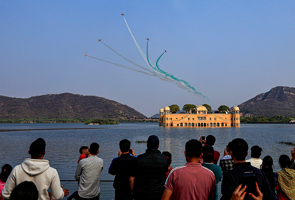 | Photo: PTI : Indian Air Force's (IAF) Surya Kiran Aerobatic Team (SKAT) performs manoeuvres over the Jal Mahal during full dress rehearsal ahead of the Sarang and Surya Kiran Air Show, in Jaipur, Rajasthan.