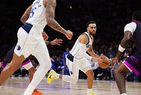 Dallas Mavericks' Tyus Jones, center, controls the ball against the Minnesota Timberwolves during the second half of an NBA basketball game in Minneapolis.