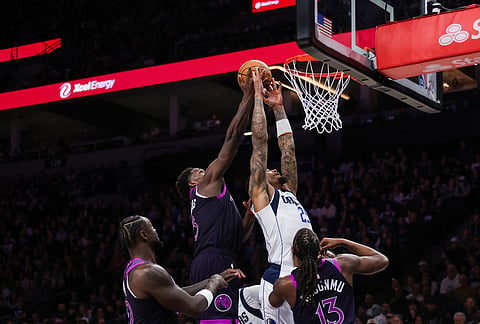 Minnesota Timberwolves' Anthony Edwards (5) reaches to block Dallas Mavericks' P. J. Washington Jr., top right, during the second half of an NBA basketball game in Minneapolis.