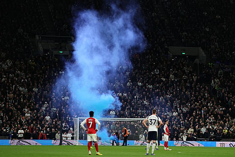 Firemen try to extinguish a flare during the English Premier League soccer match between Tottenham Hotspur and Arsenal in London.