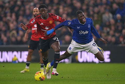 Manchester United's Kobbie Mainoo tackles Everton's Thierno Barry during the Premier League soccer match between Manchester United and Everton in Liverpool, England.
