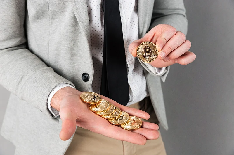 Man in a suit holding several gold Bitcoin coins