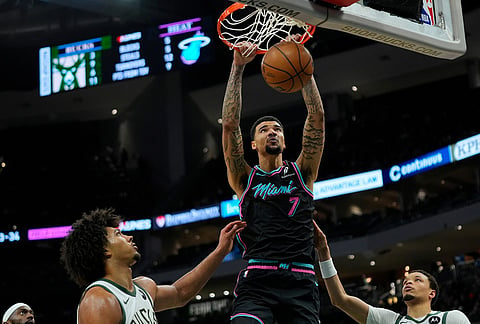 Miami Heat's Kel'el Ware (7) dunks over Milwaukee Bucks' Jericho Sims and Ryan Rollins during the second half of an NBA basketball game in Milwaukee. 