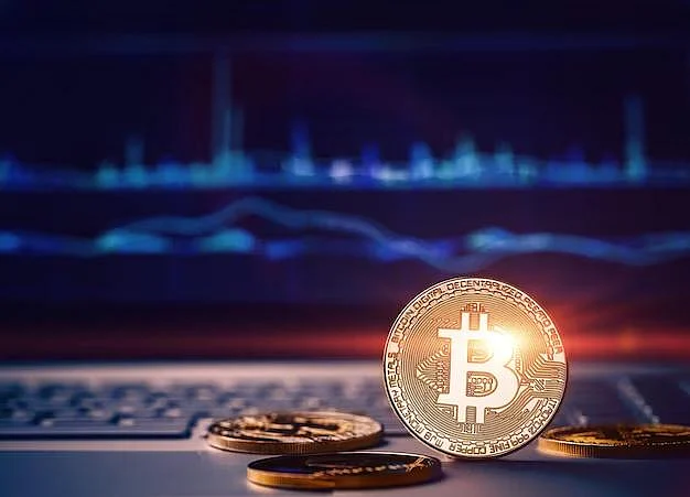 Bitcoin coins on a laptop with a trading chart
