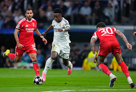 Real Madrid's Vinicius Junior, center, and Benfica's Nicolas Otamendi, right, challenge for the ball during the second leg of the Champions League playoff soccer match between Real Madrid and Benfica in Madrid, Spain.