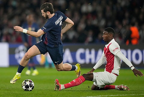 Monaco's Vanderson tackles PSG's Khvicha Kvaratskhelia during a Champions League second leg playoff soccer match between Paris Saint-Germain and Monaco in Paris.