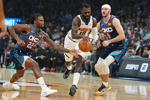 Denver Nuggets guard Tim Hardaway Jr. (10) drives past Oklahoma City Thunder guards Cason Wallace (22) and Alex Caruso (9) during the first half of an NBA basketball game in Oklahoma City.