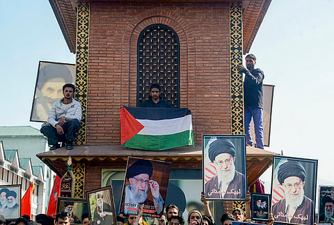 Protesters hold portraits of Iran's Supreme Leader Ali Khamenei and and Palestinian flags during a protest against the alleged killing of Khamenei in US-Israel strikes, at Ghanta Ghar, in Srinagar.