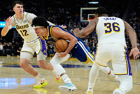 Golden State Warriors forward Gui Santos, center, moves the ball between Los Angeles Lakers forward Jake LaRavia (12) and guard Marcus Smart (36) during the second half of an NBA basketball game in San Francisco. 