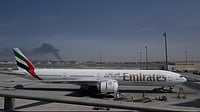 Iran Hits Back: Targets US Assets, Allies Across West Asia Altaf Qadri : A plume of smoke caused by an Iranian strike is seen in the background an an Emirates plane is parked at the Dubai International Airport after its closure in Dubai, United Arab Emirates, Sunday, March 1, 2026.