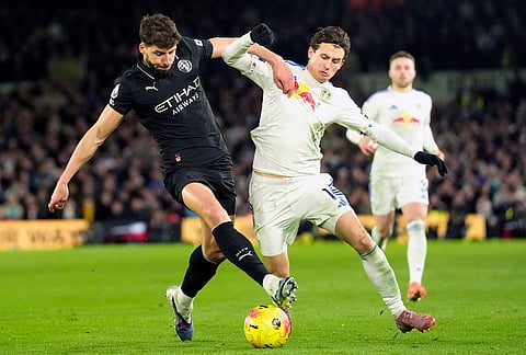 Manchester City's Ruben Dias, left, and Leeds United's Brenden Aaronson battle for the ball during the Premier League soccer match between Leeds United and Manchester City in Leeds, England.