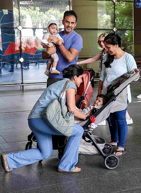 A woman reacts on meeting her husband and twin infants upon their arrival from Abu Dhabi at the Chhatrapati Shivaji Maharaj International Airport amid disruptions to flight services caused by escalating conflict in the Middle East, in Mumbai.