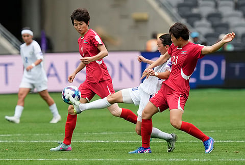 Uzbekistan's Diyorakhon Khabibullaeva, centre, battles for the ball with North Korea's Ri Hye Gyong, right, and Myong Yu Jong during the Women's Asia Cup soccer match between North Korea and Uzbekistan in Sydney.