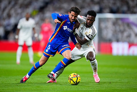 Real Madrid's Vinicius Junior fights for the ball against Getafe's Luis Milla during a Spanish La Liga soccer match between Real Madrid and Getafe in Madrid, Spain.