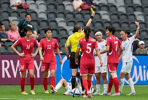 Referee Casey Rebelt shows a yellow card to North Korea's Myong Yu Jong, second right, during the Women's Asia Cup soccer match between North Korea and Uzbekistan in Sydney.