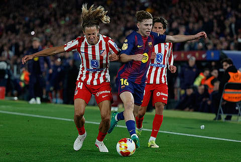 Atletico Madrid's Marcos Llorente, left, and Barcelona's Fermin Lopez challenge for the ball during the Copa del Rey semifinal second leg soccer match between Barcelona and Atletico Madrid in Barcelona, Spain.