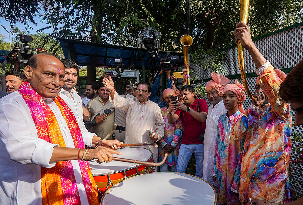 | Photo: PTI/Kamal Kishore : Union Defence Minister Rajnath Singh plays a traditional instrument with others during the Holi festival celebration at his residence, in New Delhi.