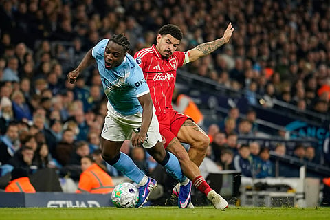 Manchester City's Jeremy Doku, left, is challenged by Nottingham Forest's Morgan Gibbs-White during the English Premier League soccer match between Manchester City and Nottingham Forest in Manchester, England.