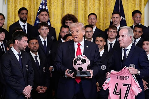 President Donald Trump holds a signed soccer ball and Tudor Black Bay watch as Inter Miami CF owner Jorge Mas Santos and Lionel Messi listen at an event to honor the 2025 Major League Soccer champions Inter Miami CF in the East Room of the White House in Washington.