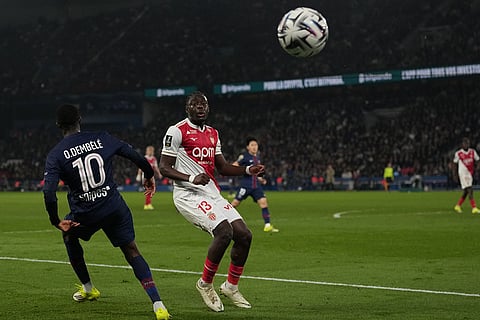 Monaco's Christian Mawissa, right, watches the ball past PSG's Ousmane Dembele during the French League One soccer match between Paris Saint-Germain and Monaco in Paris.