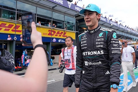Mercedes driver George Russell of Britain walks down pit lane after winning the qualifying session for the Australian Formula One Grand Prix at Albert Park, in Melbourne, Australia.