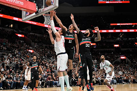 Los Angeles Clippers center Brook Lopez, left, goes to the basket against San Antonio Spurs' Carter Bryant, center, and Julian Champagnie during the second half of an NBA basketball game in San Antonio.